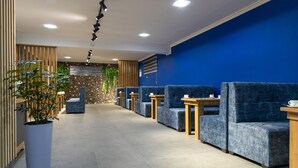 A modern reception area with blue upholstered seating, a potted plant, and a stone wall in the background. - THE TIME HOTEL (Tashkent)
