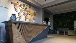 A reception desk with a world map mural, a reception area with seating, and a green wall. - THE TIME HOTEL (Tashkent)