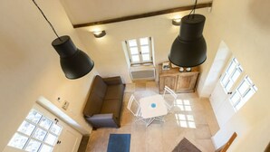 Una habitación con techos altos, un comedor, un banco empotrado y una pequeña kitchenette.