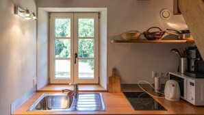 Una cocina con un lavamanos, un microondas y una estufa. Se ve una ventana con vistas a árboles.