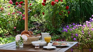 A breakfast table set outdoors with a variety of bread, a glass of orange juice, and a plate of food. - Hotel Dreiflüssehof Gästehaus (Passau)