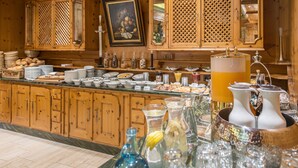 A buffet area with wooden cabinets, a painting, and various food items. - Hotel Dreiflüssehof Gästehaus (Passau)