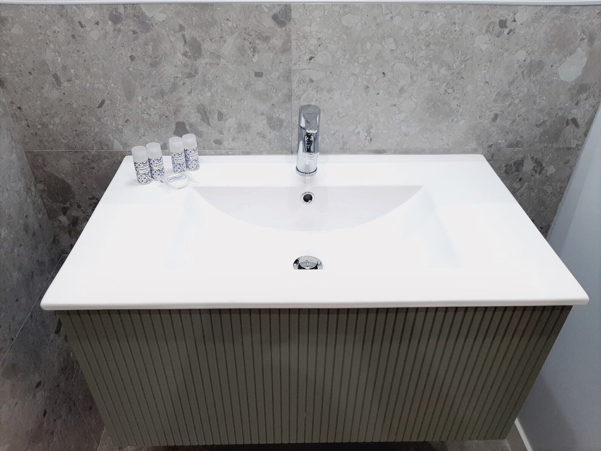 Un baño con un lavabo blanco, un grifo y tres botellas de jabón para manos.