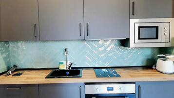 A kitchen with grey cabinets, a microwave, a toaster, and a dishwasher.