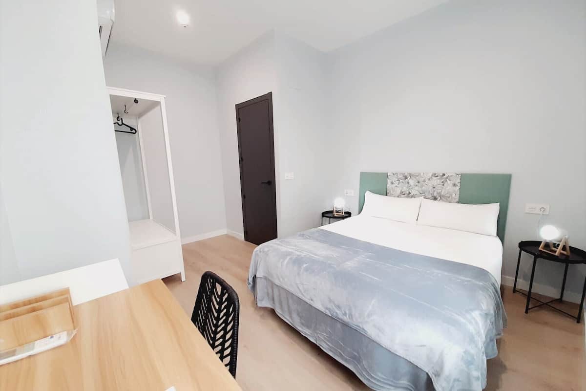 A bedroom with a bed, a desk, and a chair.