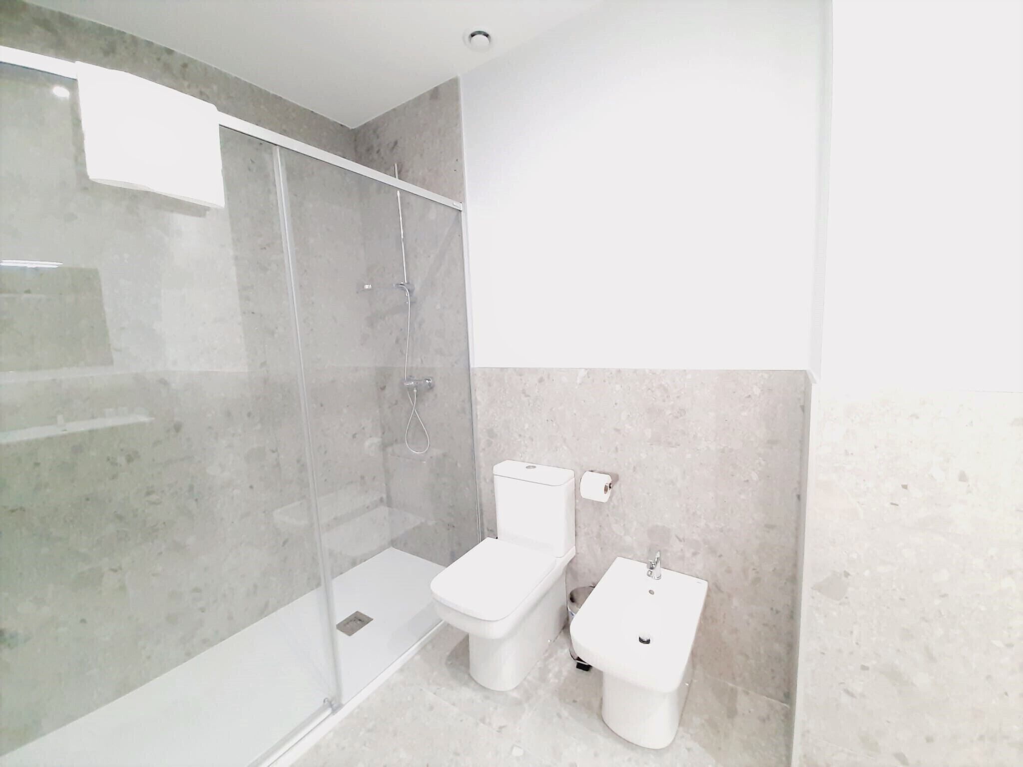 Un baño con ducha envuelta en vidrio, inodoro y bidé.