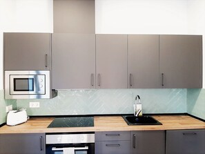 A modern kitchen with grey cabinets, a microwave, a toaster, and a sink.