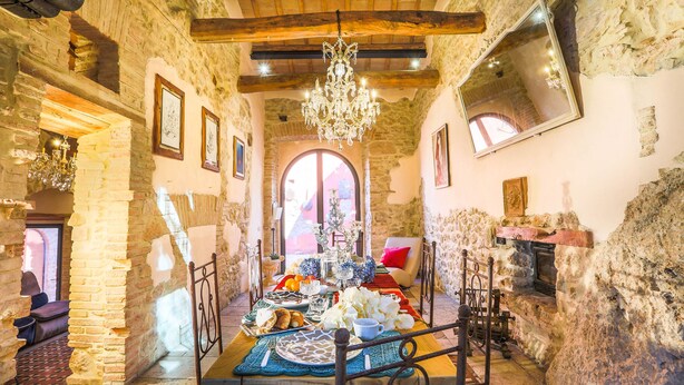 A rustic stone interior with a chandelier, a fireplace, and a dining area with a table set for a meal. - Villa in the historical center with private garden, pool, spa and AC (Narni)