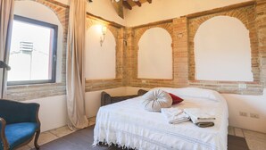 A bedroom with a large bed, a chair, and a window with curtains. - Villa in the historical center with private garden, pool, spa and AC (Narni)
