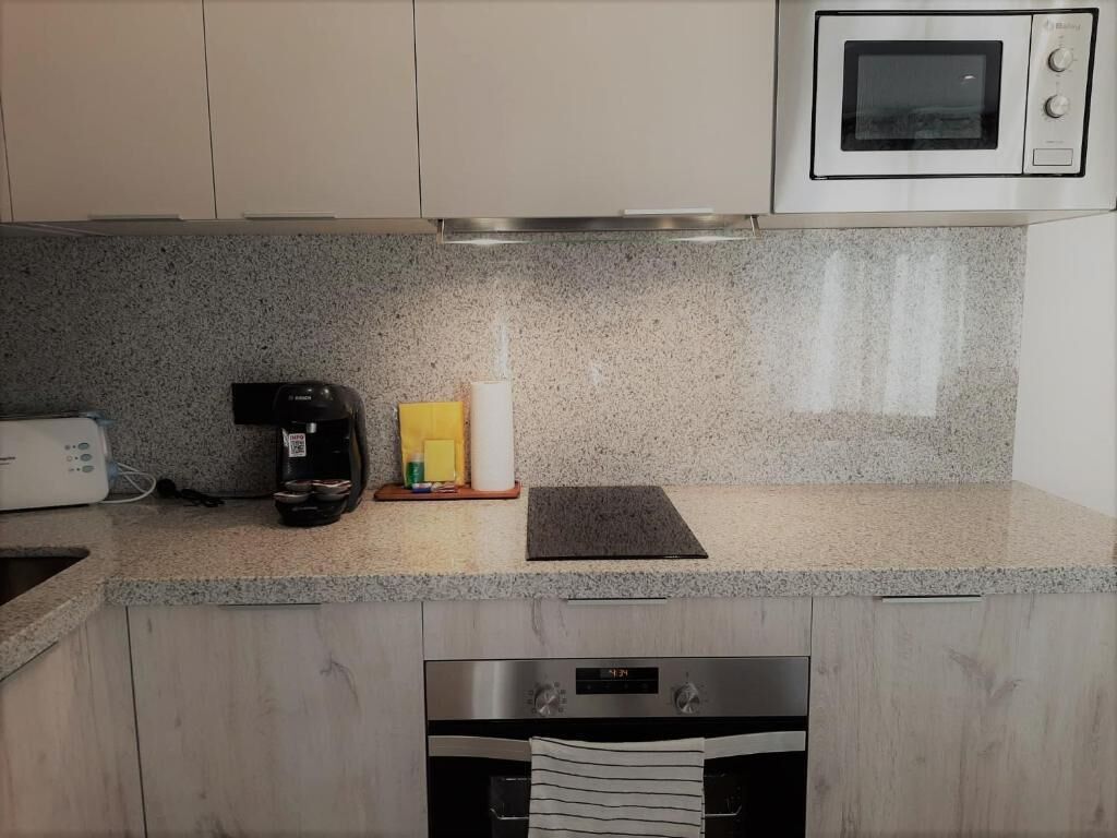 A kitchen with granite countertops, a coffee maker, a toaster, and a microwave.
