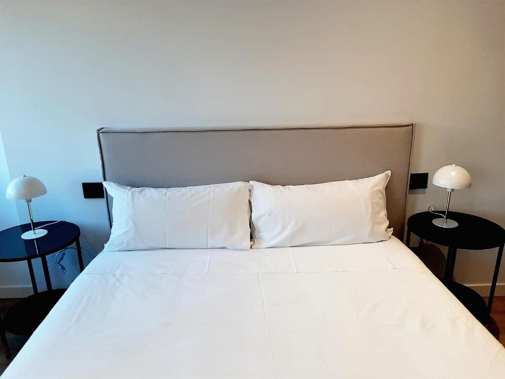 A hotel room with a bed, two bedside tables, and two lamps.