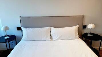 A hotel room with a bed, two bedside tables, and two lamps.