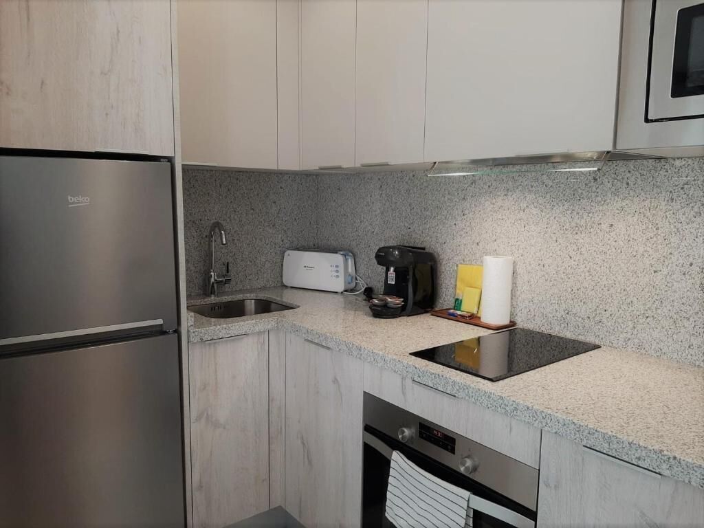 Eine moderne Küche mit einem Einbaukühlschrank, einem Toaster, einer Kaffeemaschine und einem Spülbecken.