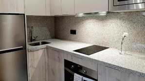 A modern kitchen with stainless steel appliances, granite countertops, and white cabinetry. - Apartamentos Celestina by gaiarooms (Salamanca)