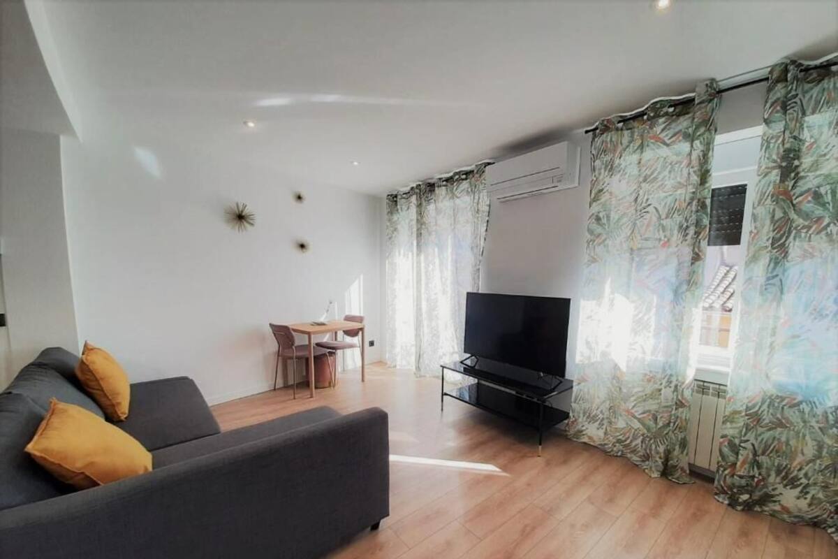 A modern living room with a sofa, a TV, and a dining area.
