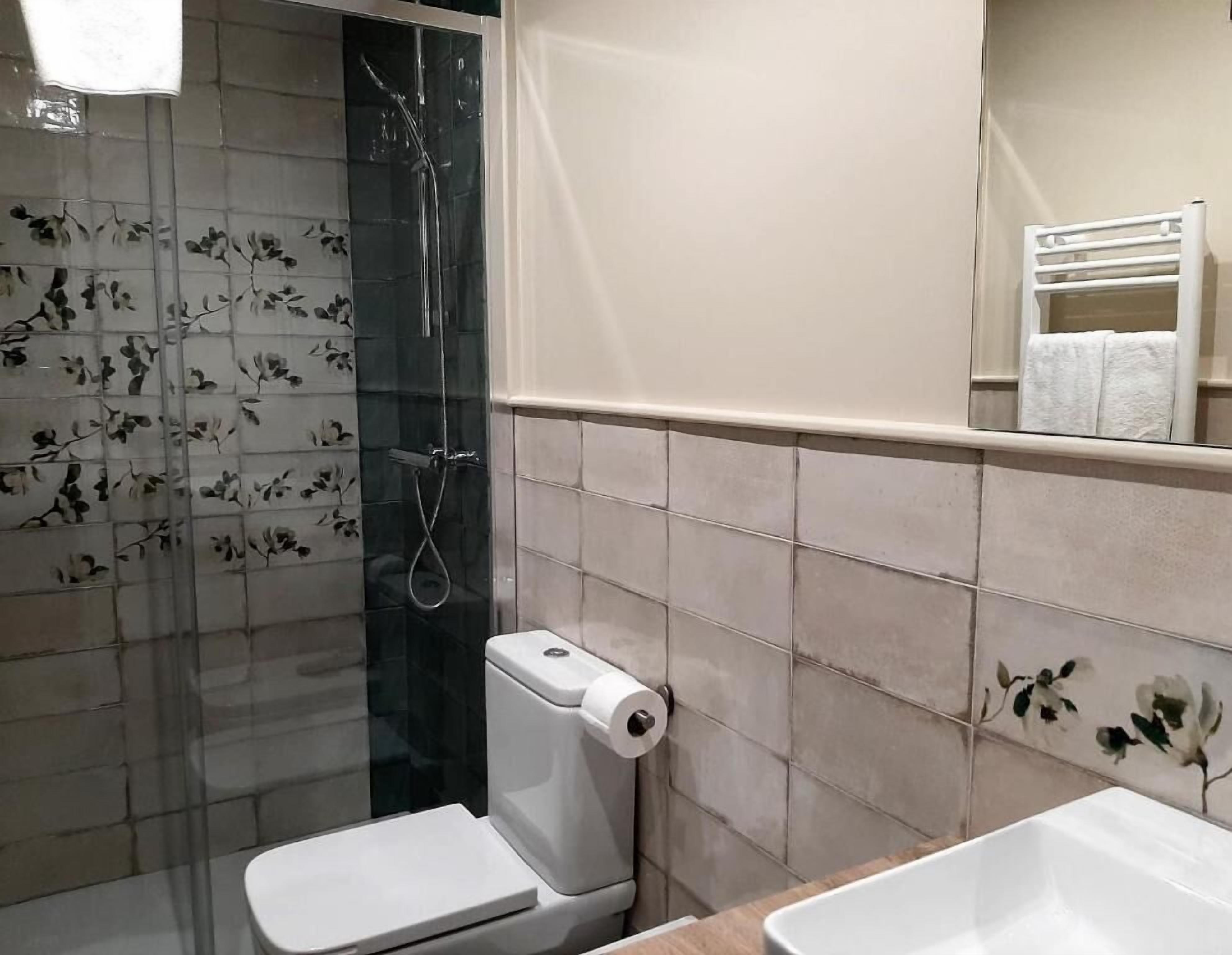 A bathroom with a toilet, a shower, and a sink.