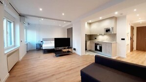 A modern apartment with a living area, kitchen, and a TV. - Apartamentos Celestina by gaiarooms (Salamanca)