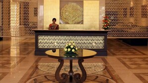 Una hall con un lampadario sontuoso, una reception, pareti decorate con motivi e un pavimento ornamentale.