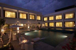 A hotel with a swimming pool, outdoor seating, and large windows. - FAIRLEY's HOTEL&RESORTS (New Delhi)