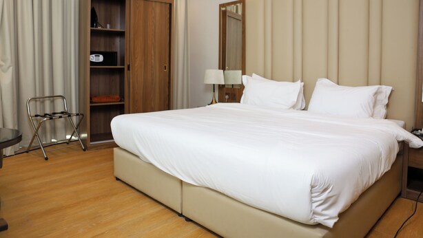Una habitación de hotel con una cama grande, un armario, un escritorio y una silla.