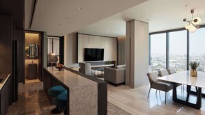 A modern kitchen with a marble countertop and bar stools, a dining area with a large table and chairs, and a living space with a TV and seating. - Dusitd2 Samyan Bangkok (Bangkok)