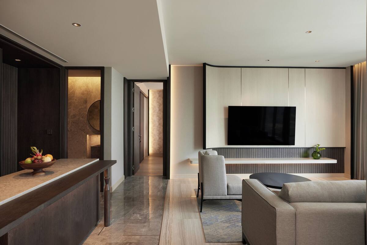 A modern living room with a flat-screen TV mounted on the wall, a sofa, and a coffee table.