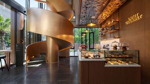A modern interior with a spiral staircase, a coffee shop area, and a sign reading "Gourmet". - Dusitd2 Samyan Bangkok (Bangkok)