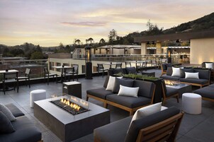 Una terraza en la azotea con mobiliario exterior, fogones y zona de bar.