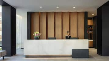 A reception desk with a modern design, a vase with flowers, and a seating area with a bench.