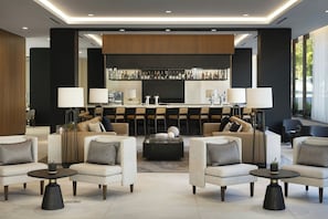 A modern lounge area with sofas, armchairs, a coffee table, and a bar with a variety of bottles. - AC Hotel San Rafael Downtown (San Rafael)