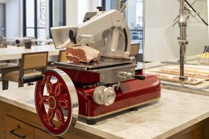Un cortador de carne con una rueda roja, sobre una encimera de mármol en una cocina.