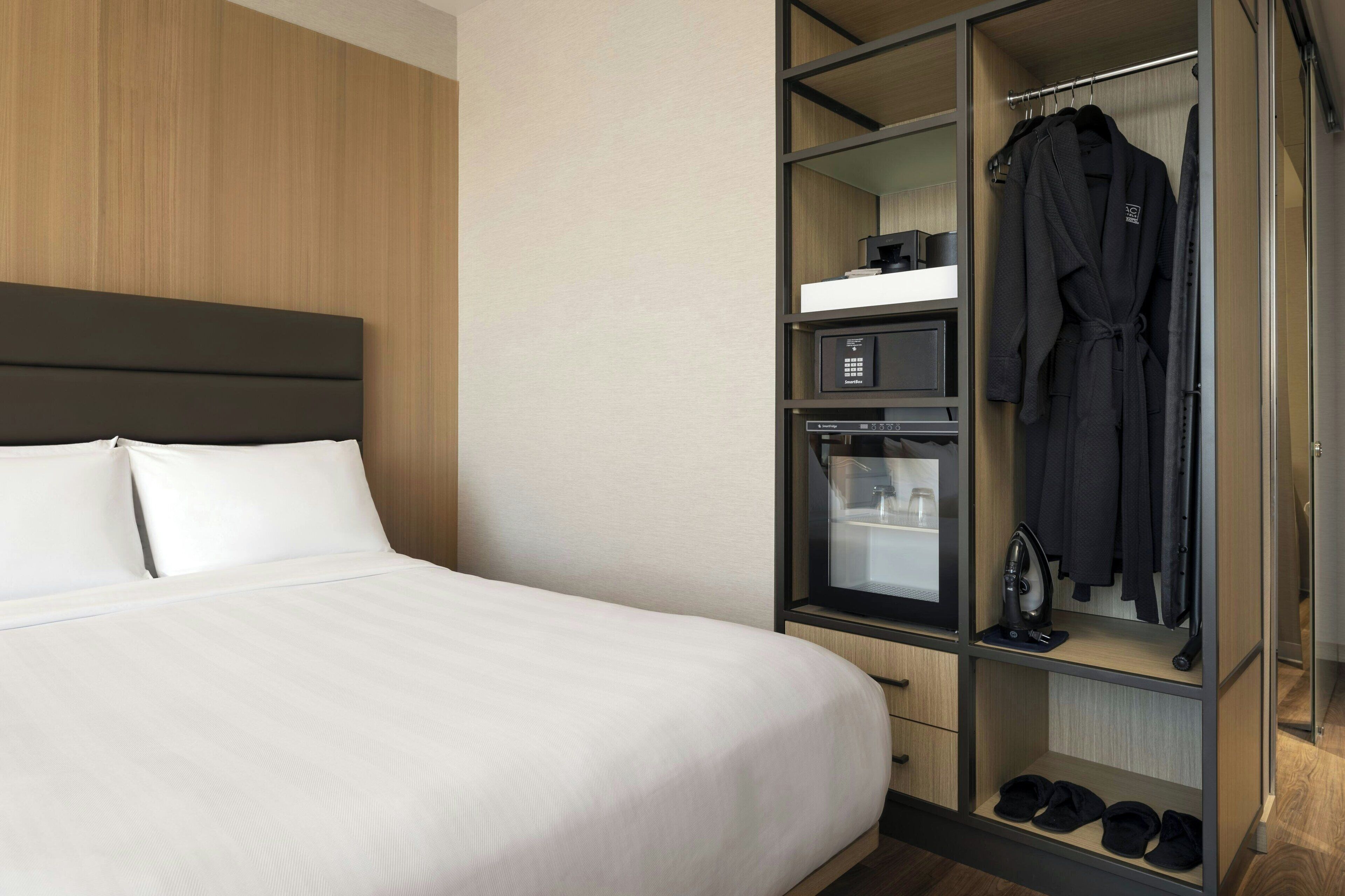 Una habitación de hotel con una cama grande, un armario con espejo y una pequeña cocina.
