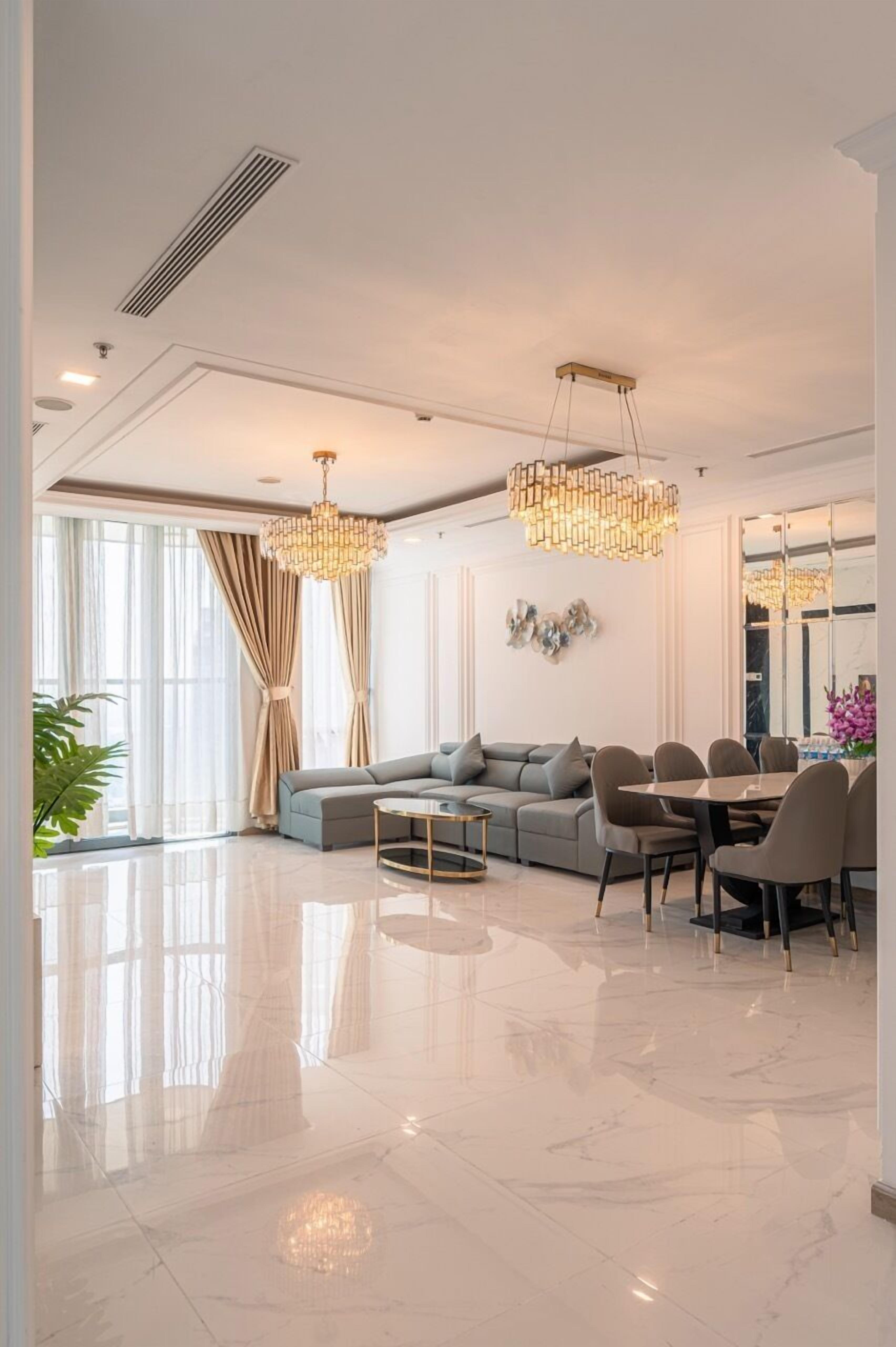 A modern living room with a sectional sofa, dining table, chairs, and pendant lighting.