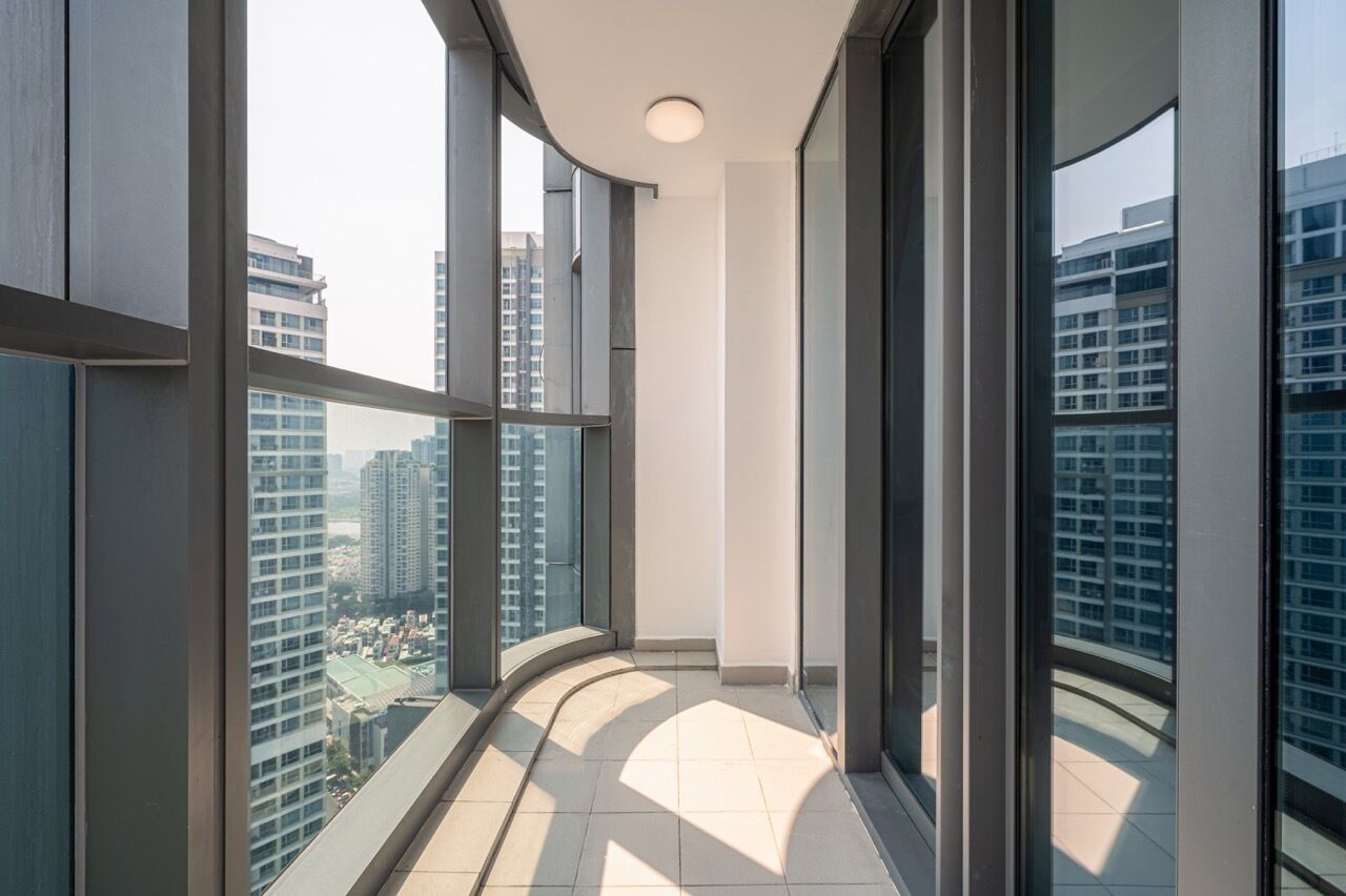 Eine hohe Wohnappartementanlage mit großen Fenstern, einem gebogenen Balkon und Blick auf andere Gebäude.