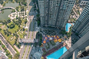 Un immeuble de grande hauteur doté d’une piscine sur le toit et d’un parc aménagé avec un étang et des sentiers pédestres.