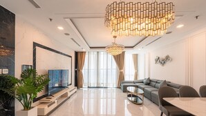 Ein modernes Wohnzimmer mit großem Fernseher, einem Esstisch und einer Chandelier.