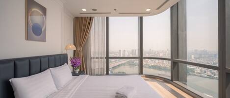 A modern hotel room with a large bed, a city view, and a large window.