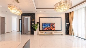 Eine moderne Hotelhalle mit Marmorboden, einem großen Flachbildfernseher, zwei Pendelleuchten und einer Zimmerpflanze.