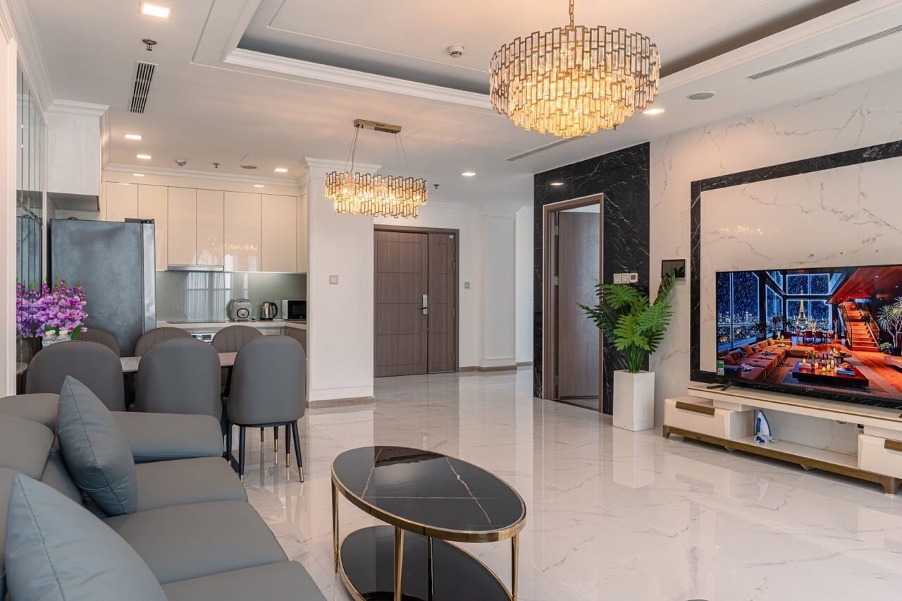 Una sala moderna con un sofá, una mesa de comedor y un televisor mostrando un paisaje urbano.