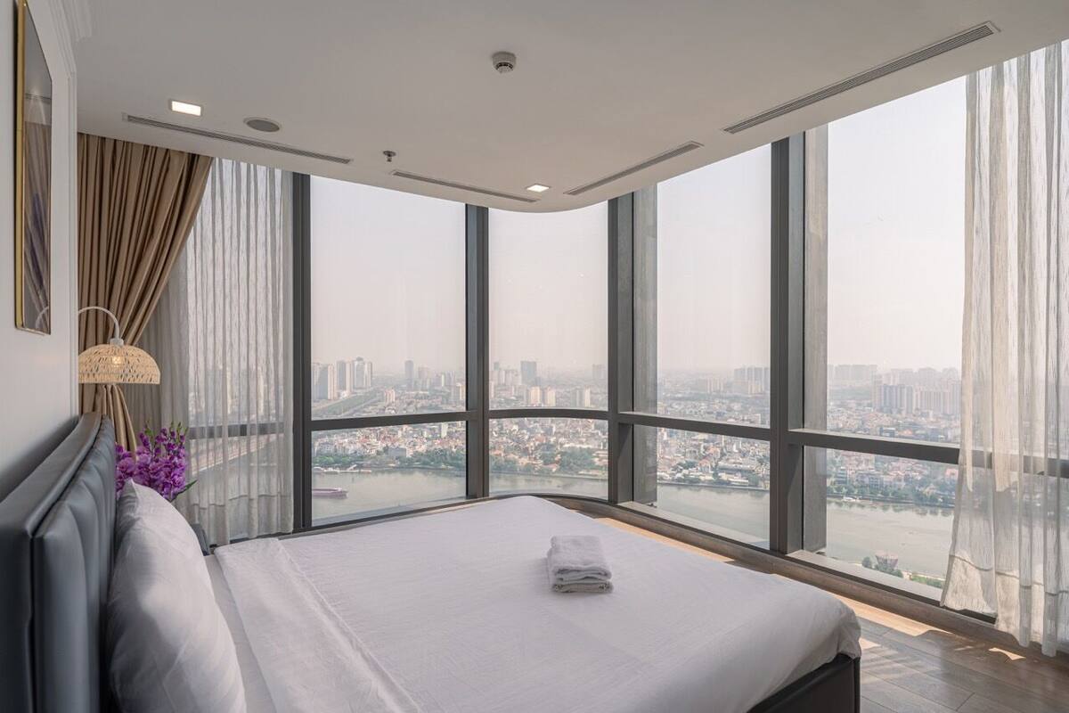 Une chambre d’hôtel située dans un immeuble de grande hauteur, dotée d’un grand lit, offrant une vue sur le paysage urbain et présentant un design moderne.