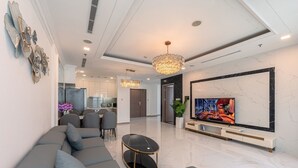 Ein modernes Wohnzimmer mit einem Ecksofa, einem Fernseher und einer Deckenleuchte.