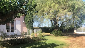Un espacio al aire libre cercado con un edificio, árboles y cielo despejado.