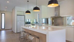 A modern kitchen with a central island, stainless steel appliances, and pendant lighting. - The Point Villa Da Nang (Da Nang)