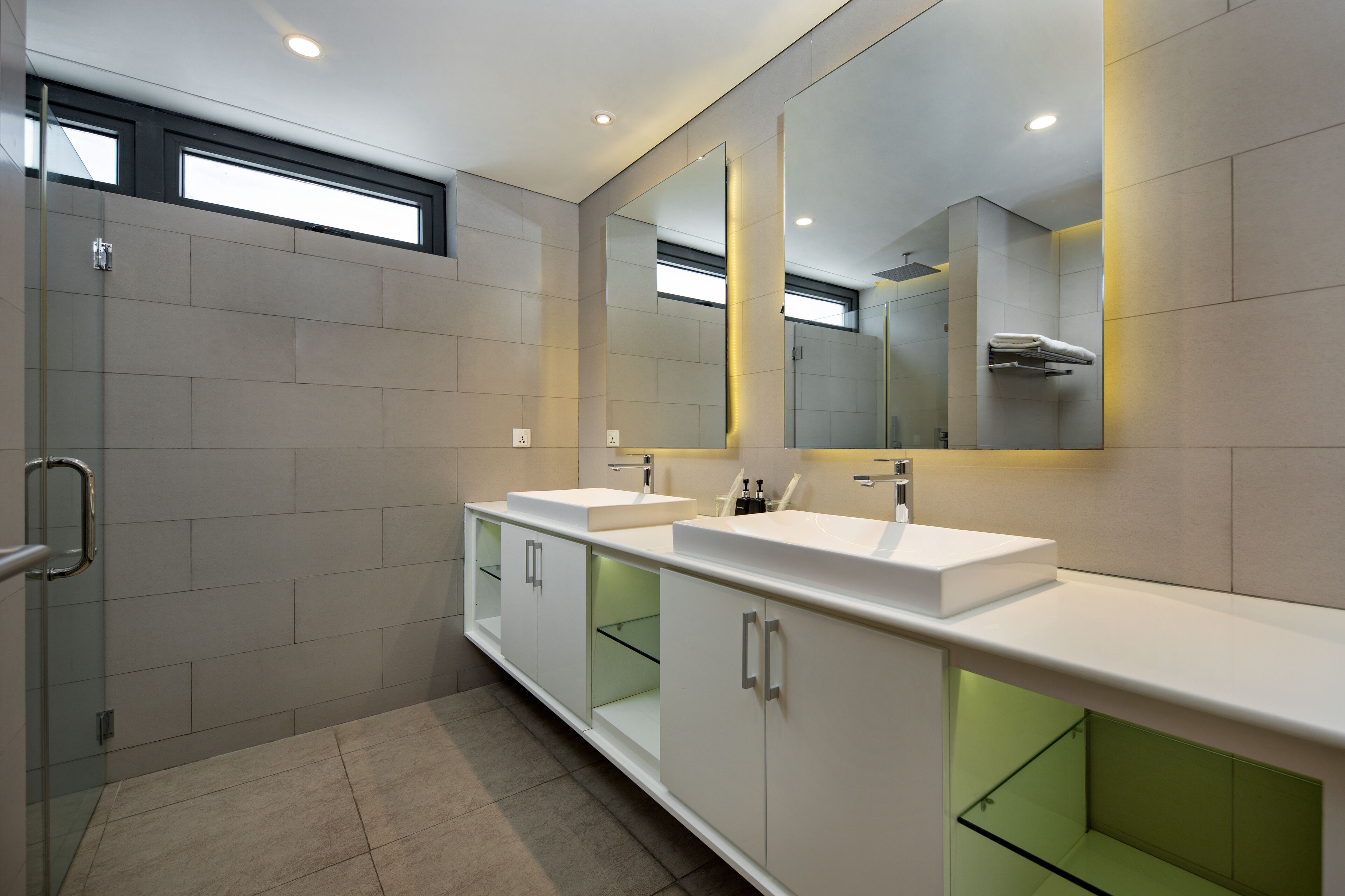 Un baño moderno con dos lavamanos, un espejo grande y cabina de ducha de vidrio.