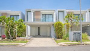 A modern residential building with a central entrance, surrounded by greenery and a clear sky. - The Point Villa Da Nang (Da Nang)