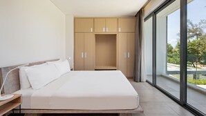 A modern bedroom with a large bed, wooden wardrobe, and a view through a large window. - The Point Villa Da Nang (Da Nang)