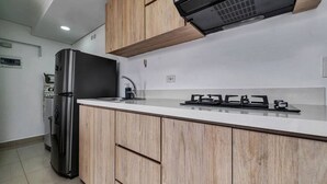 A modern kitchen with wooden cabinets, a stainless steel refrigerator, and a gas stove.