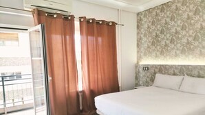 Un dormitorio con cama, cortinas, una ventana y una pared con estampado floral.