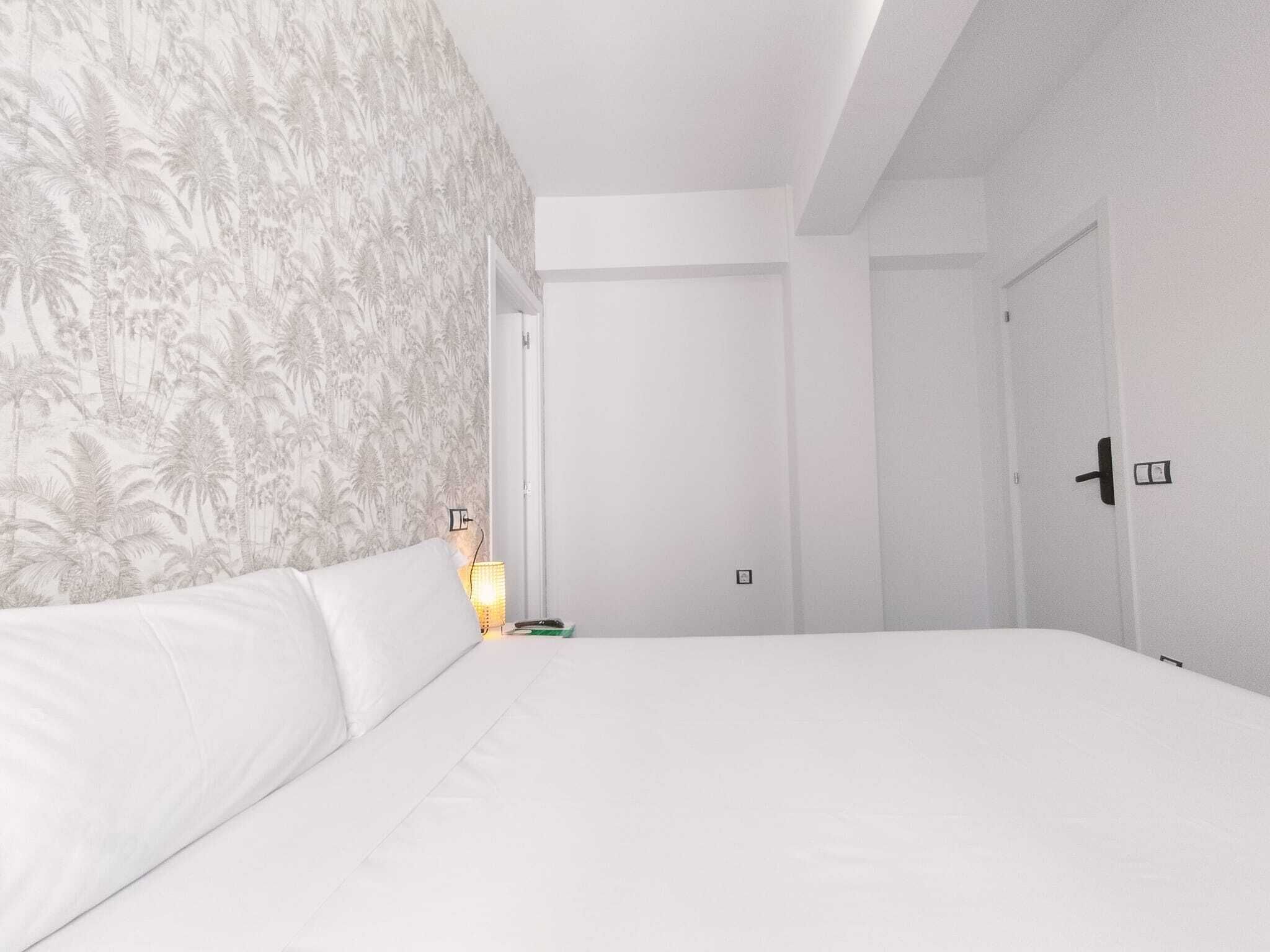 Un dormitorio con una cama, una mesita de noche, una lámpara y una puerta.