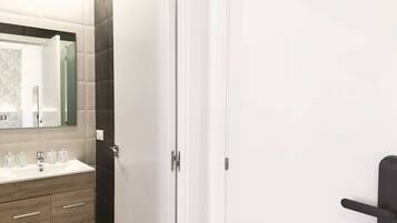 Un baño moderno con tocador blanco, baldosas oscuras y pomo negro.